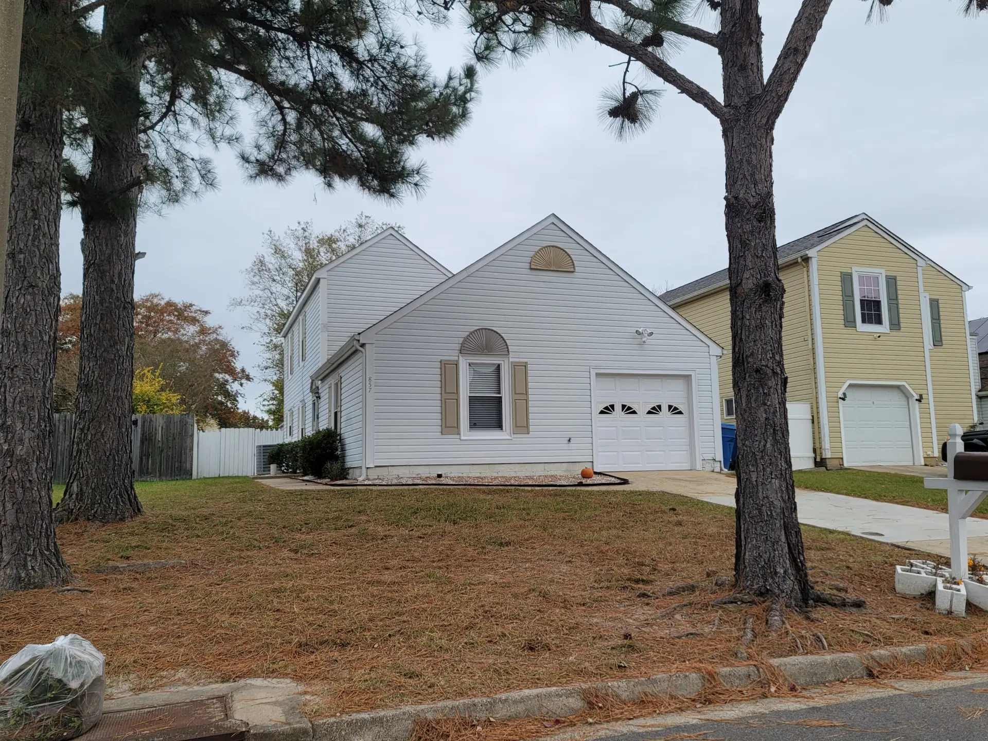 White home with an attached garage and trees in the front yard