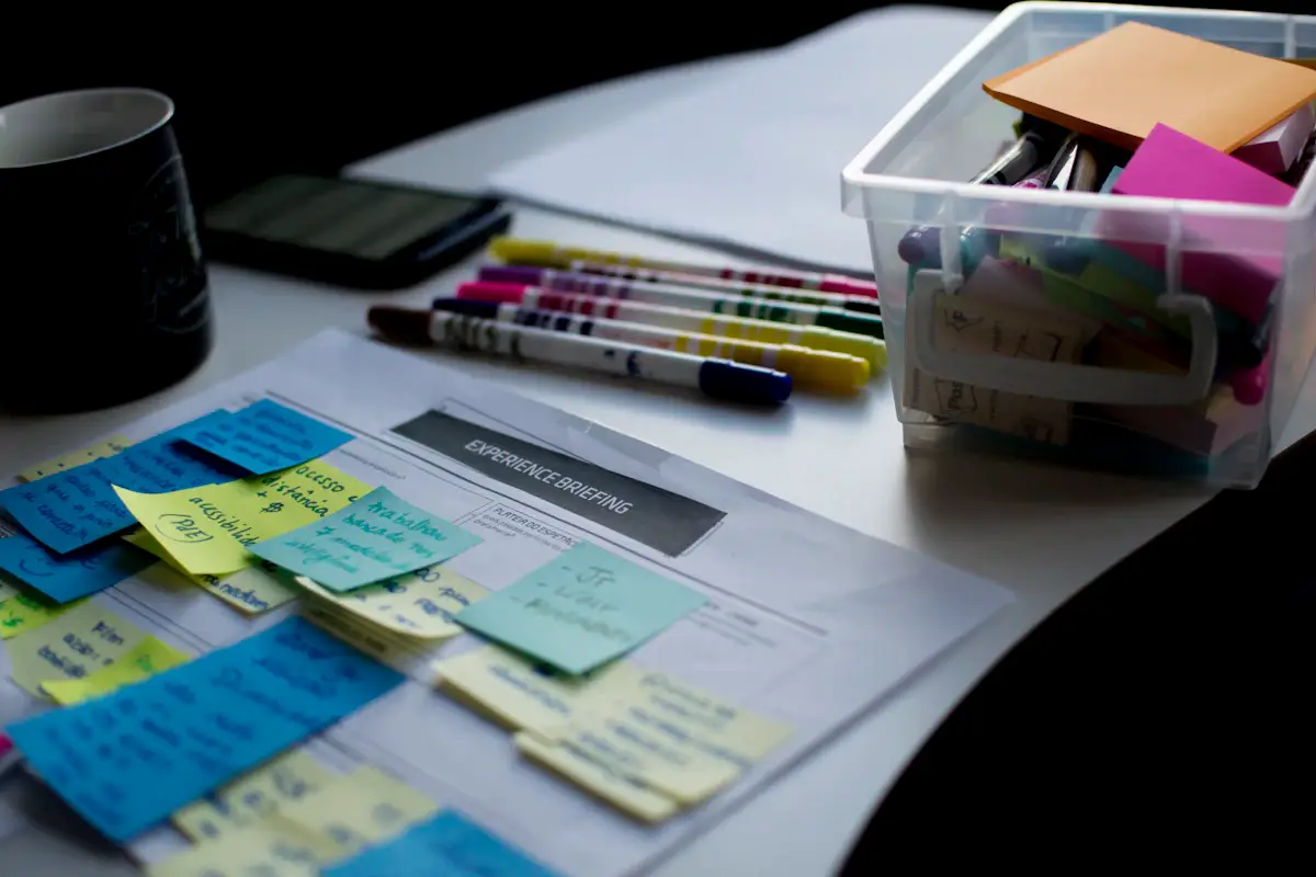 Sticky notes on a paper document beside pens and a box