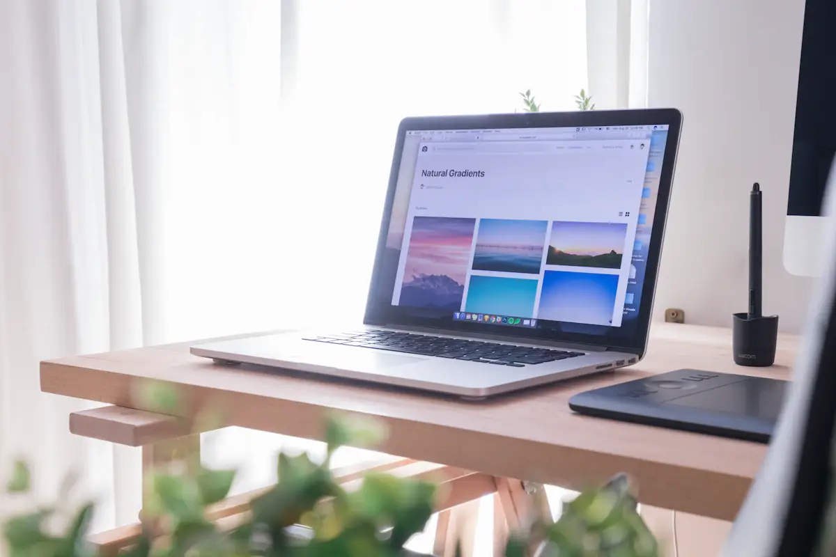 Open laptop on a wooden desk beside a window
