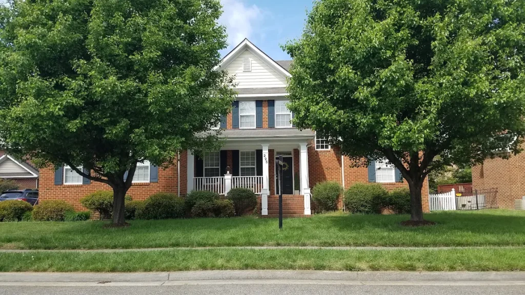Brick home with a white front porch framed by mature trees