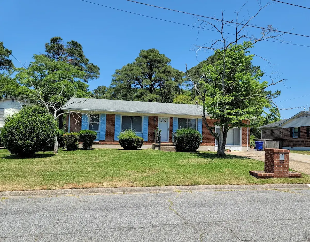 Brick ranch home with a blue front door and green lawn