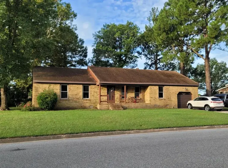 Brick ranch home with a broad lawn and mature trees