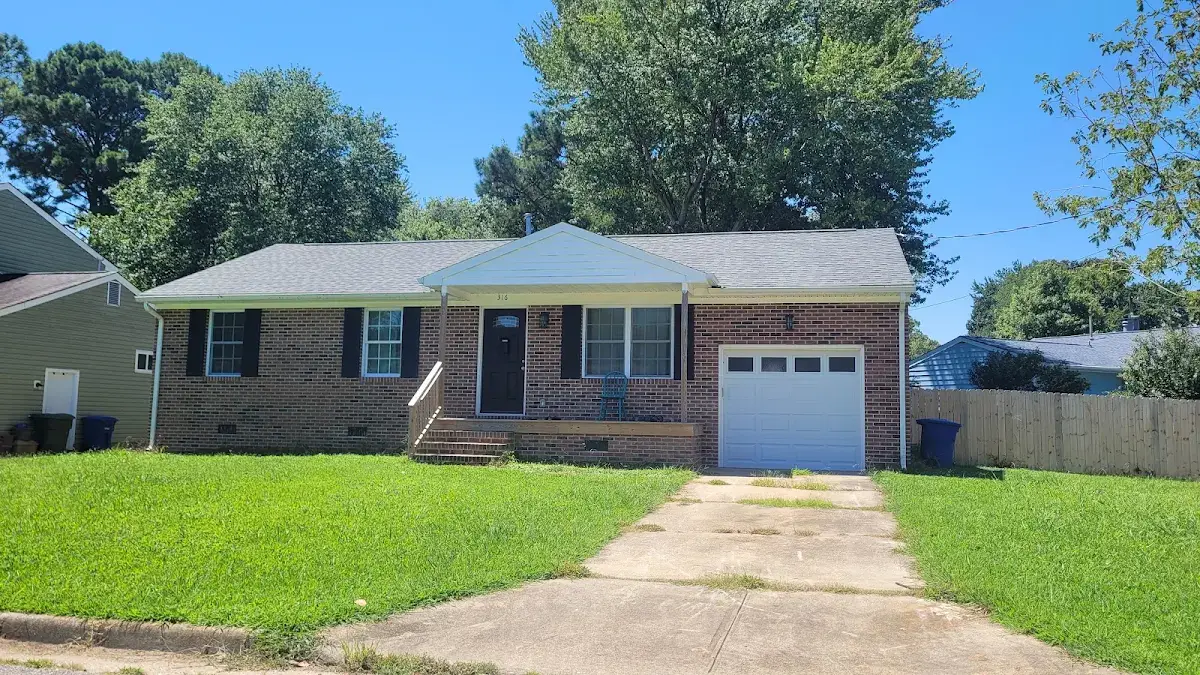 Brick ranch home with a white garage and sunny green lawn