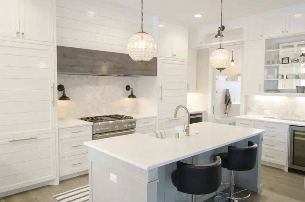 Renovated kitchen with white cabinets, an island and pendant lighting