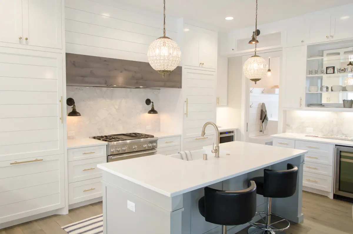 Renovated kitchen with white cabinets, an island and pendant lighting