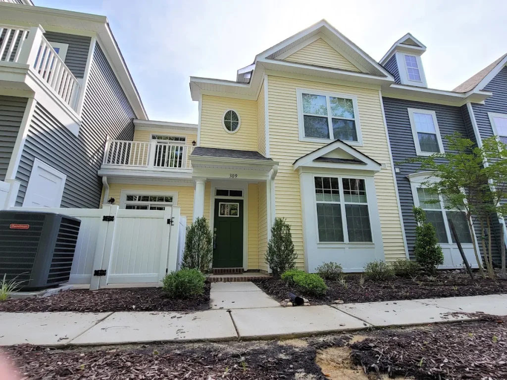 Tall yellow residence with white porch railings and fencing