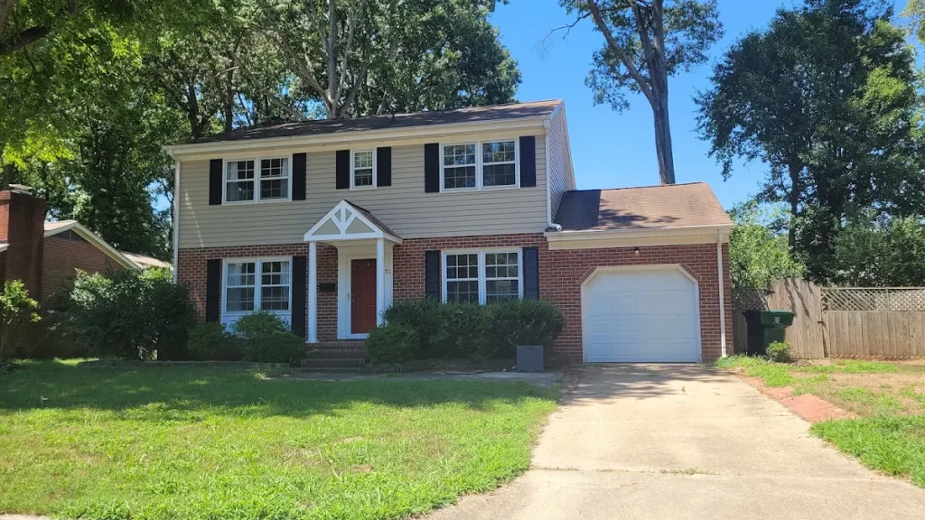 Two-story brick and yellow-sided home with shutters and a white entrance