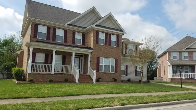 Two-story brick home with a front porch and maroon shutters