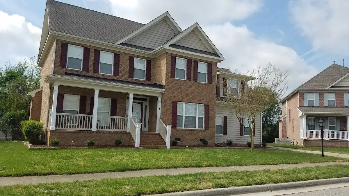 Two-story brick home with a front porch and maroon shutters