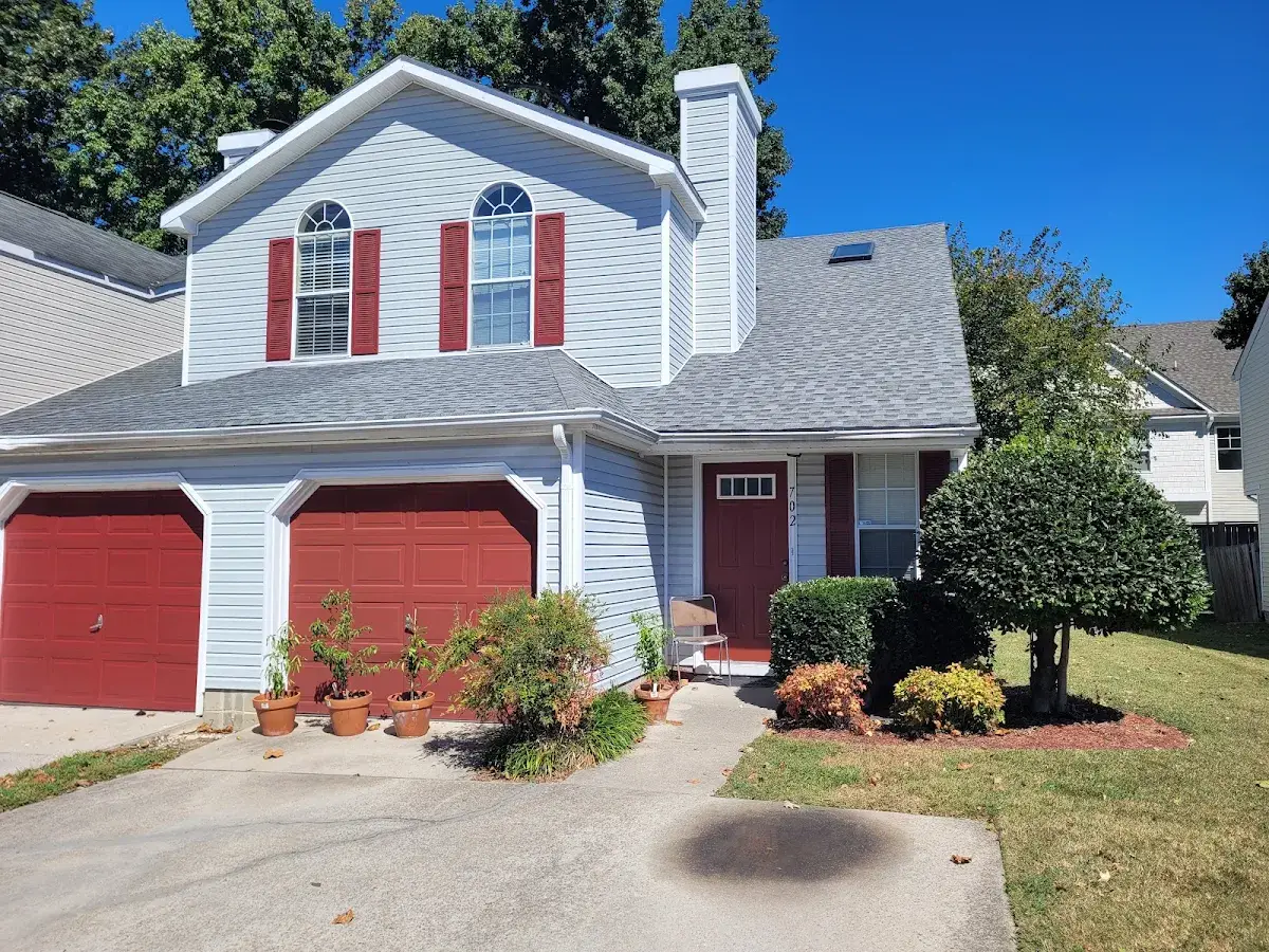 White home with red garage doors, red shutters, and roof dormers