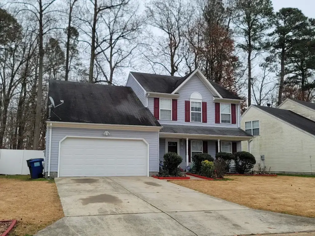 White two-story home with red shutters, a front porch, and an attached garage